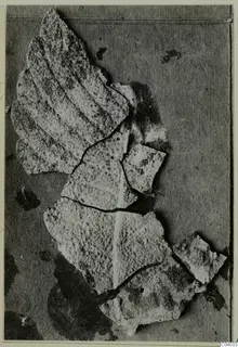 Corroded bronze mounting fragments lying together on a dark card