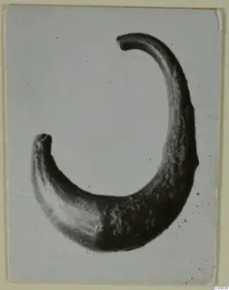 Curved metal ornament from Idalion with thickened, rounded ends, shown on a grey card mount