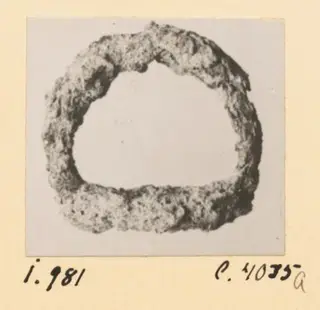 Corroded iron ring from Idalion, photographed on a grey card mount