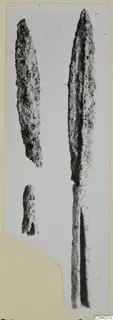 Iron weapon pieces: a long leaf-shaped blade and two smaller fragments, photographed on a card mount.