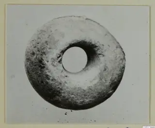 Ring-shaped stone object with a central hole, photographed on a plain light background.