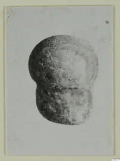 Small find from Idalion: a double-lobed object with a dark groove, shown in a photograph mounted on a card.