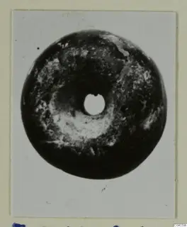 Dark disc-shaped piece of jewellery with a central hole, from Idalion