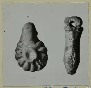 Two small finds on a card mount: a lobed pear-shaped piece and an elongated pendant with a hole at the top.
