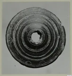 Flat disc with a central hole, concentric grooves and small crescent-shaped marks around the rim.