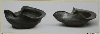 Two dark terracotta lamps with pinched spouts, photographed side by side