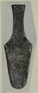 Corroded bronze object, flat and elongated, with a narrow top and small holes along its edges, shown on a grey ground.