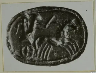 Oval stone seal with an engraved animal figure, shown in a photograph on a card mount