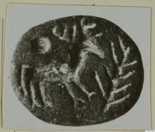 Engraved oval seal stone with pale incised lines, photographed on a white card