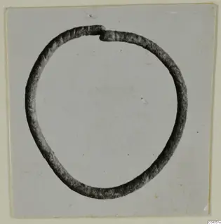 Bronze ring or bracelet, open with overlapping ends, shown in profile against a pale background