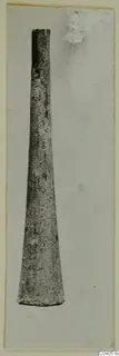 Iron object, long and tapering, shown upright on a pale mounted photograph card