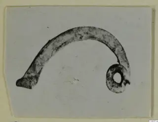 Curved bronze object with a coiled ring at one end, personal adornment from Idalion