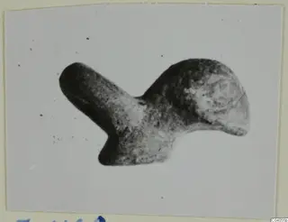Fragment of a bronze mounting from Idalion, a rounded metal piece with one narrow arm, shown on a card mount