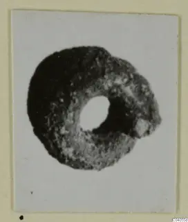 Ring-shaped bronze personal adornment with a large central hole, photographed on a mounted card