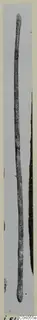 Long slender bronze rod with rounded ends, photographed upright against a grey background