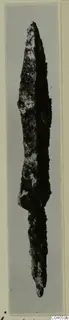 Corroded iron blade, pointed at the top and tapering at the bottom, photographed upright against a grey background.