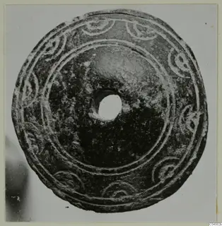 Disc-shaped piece of jewellery with a central hole and curled pattern in relief, from Idalion