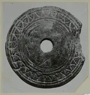 Flat disc with a central hole, incised concentric lines and an arc pattern around the edge, small find from Idalion