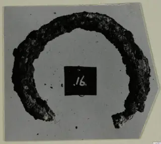 Corroded ring-shaped object from Enkomi Tomb 6, open at the lower part, with a number label placed in the centre