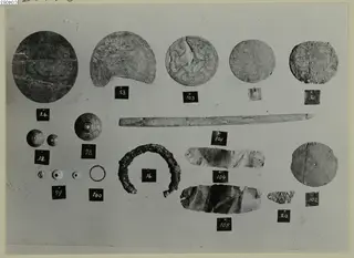 Finds from Enkomi Tomb 6 laid out in rows on a grey surface, each with a small numbered label.