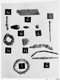 Numbered metal finds and beads from Enkomi Tomb 8, laid out on a pale background
