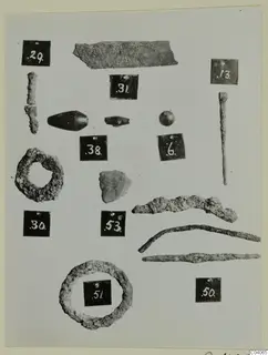 Corroded metal finds and beads from Enkomi Tomb 8, each beside a black numbered label.