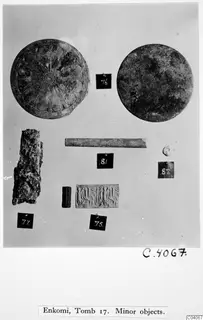 Mounted photograph of minor finds from Enkomi Tomb 17: two bronze discs, a bronze rod, a cylinder seal and a corroded lump.