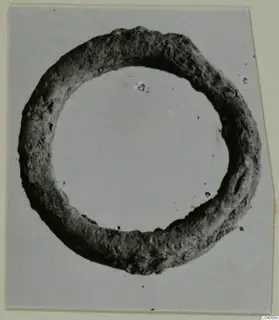 Corroded ring-shaped metal object from Enkomi Tomb 18, seen face-on