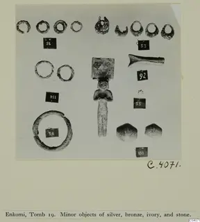 Photo mount of small finds from Enkomi E.19: rings, a small standing figure, a tapering object and two faceted stone pieces.
