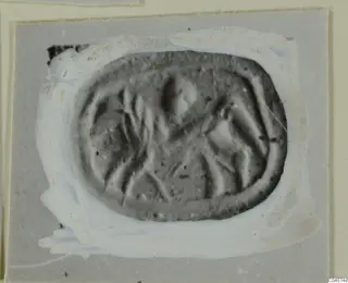 Impression of an oval seal or gem with incised linear design, shown on a grey card