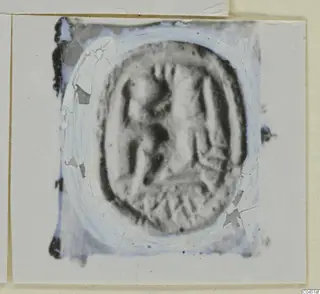 Oval seal or gem with carved figures, cracked and damaged, mounted on a card
