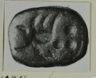Engraved dark stone seal with a rounded, almost rectangular outline, shown in a photograph