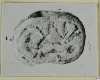 Oval seal or gem with incised marks and lines, shown face-on on a mounted card