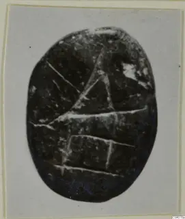 Oval dark stone seal or gem with incised linear design, shown on a mounted card