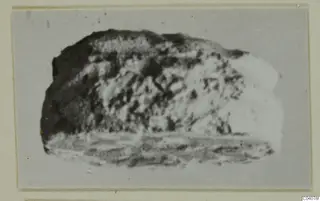 Blurred photograph of a rounded stone object from Ayia Irini, mounted on a grey card with a cream border