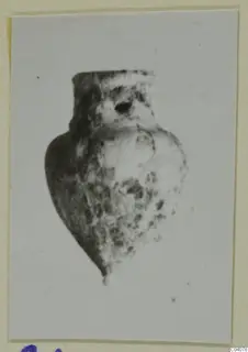 Small pendant-like object with a hole near its top, from Ayia Irini, shown on a mounted photograph.