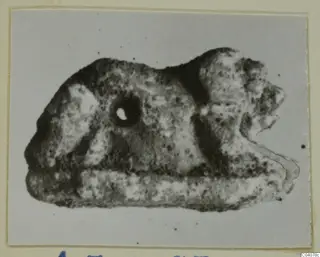 Small figure of a lion in side view, with a round hole pierced through its body near the head.