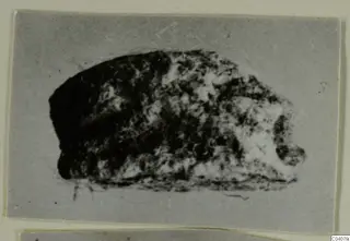 Small mottled stone object, blurred, shown on a grey mount; possibly a seal or gem from Ayia Irini