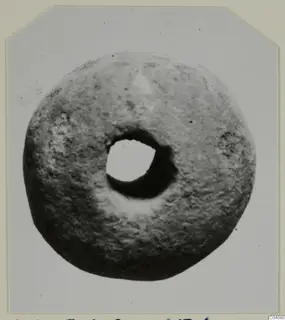 Ring-shaped stone find from Ayia Irini with a large central hole, photographed on a card mount