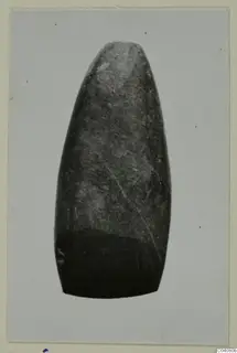 Elongated polished stone object, tapering to a rounded top, with a number label on its lower edge.
