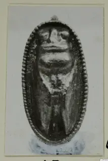 Oval pendant with a beaded rim and a face in relief, from Marion