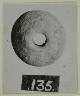 Terracotta disc with a central hole, photographed face-on with number label 135 below