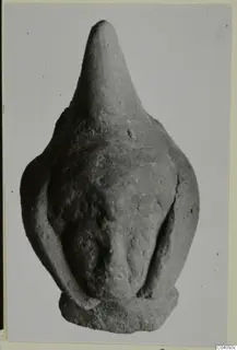 Terracotta figurine with a tall, pointed head and arms pressed against a rounded body, shown on a flat base