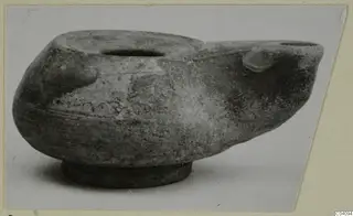 Terracotta oil lamp with a filling hole, a spout and a round base.