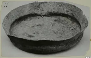 Shallow bowl with a wide, thick rim and a crack running across the rim, photographed from above at an angle.