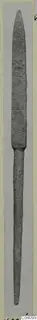 Long slender metal weapon with a pointed blade and narrow tang, photographed upright on a pale card mount.