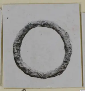 Corroded metal ring from Arsos, shown centred on a white card