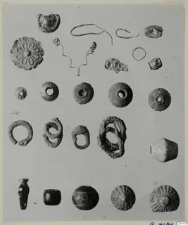 Jewellery from Arsos laid out in rows: rings, wire pins, pendants and beads, several with rosette or radiating patterns.