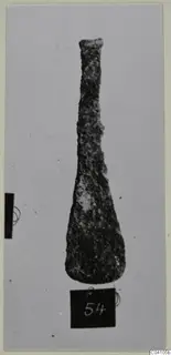 Corroded bronze tool from Ayios Iakovos Tomb 14, a long tapering blade with a narrow top and a broad rounded end.