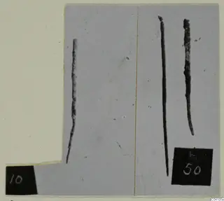 Three long, thin, corroded metal rods on a grey card, with two number labels, from Ayios Iakovos Tomb 14